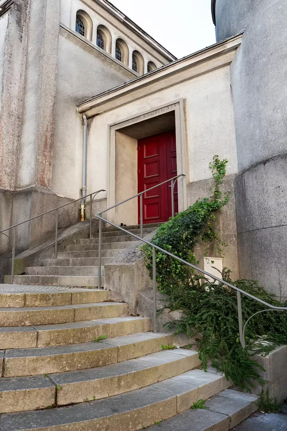 Mains courantes sur-mesure installées par Coyac sur les marches d'accès à la porte latérale rouge de l'église Notre-Dame de Toute Joie à Nantes