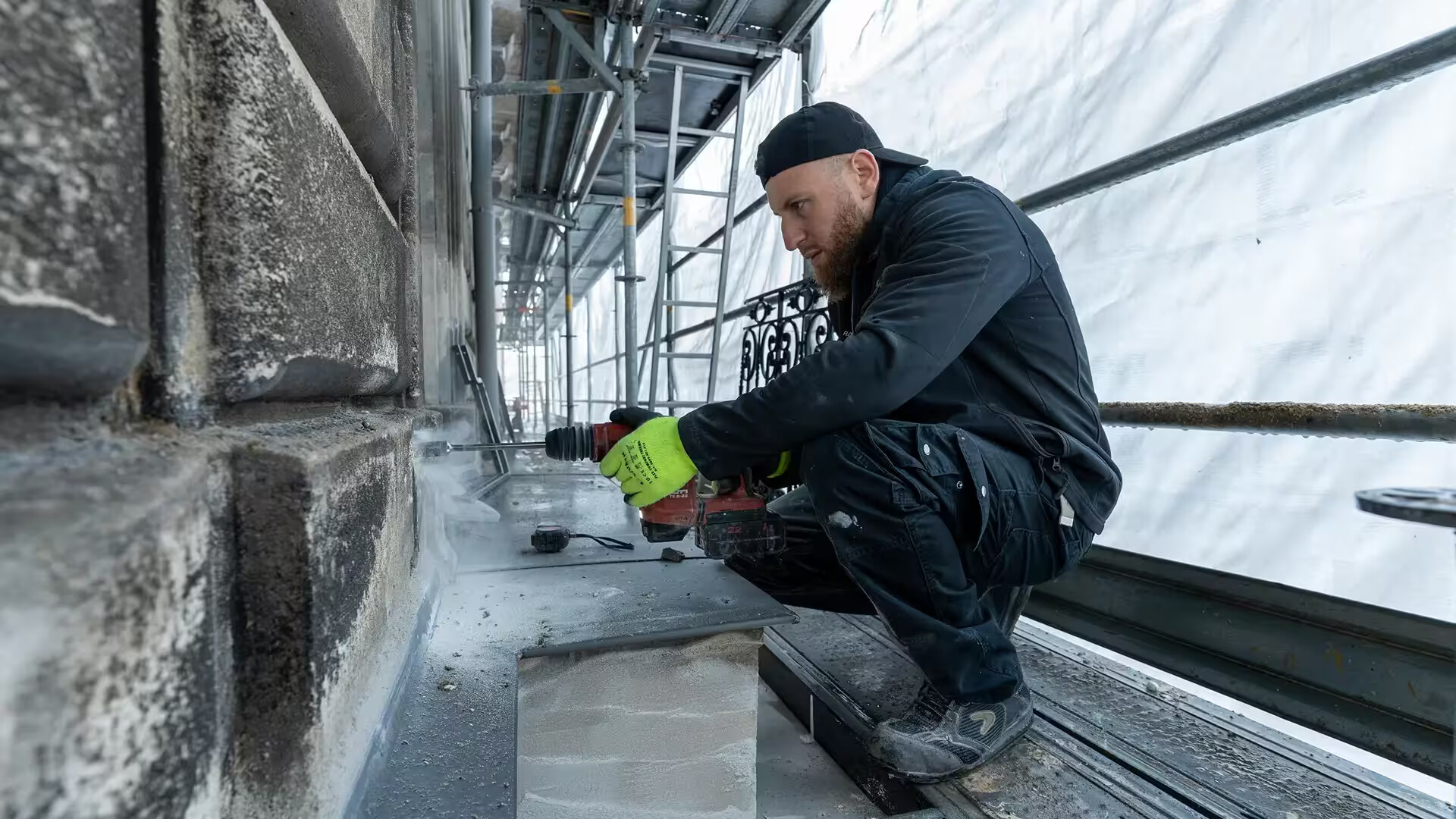 Compagnon Coyac réalisant un perçage dans la pierre pour le scellement d'un garde-corps restauré sur la façade d'un immeuble quartier Graslin à Nantes