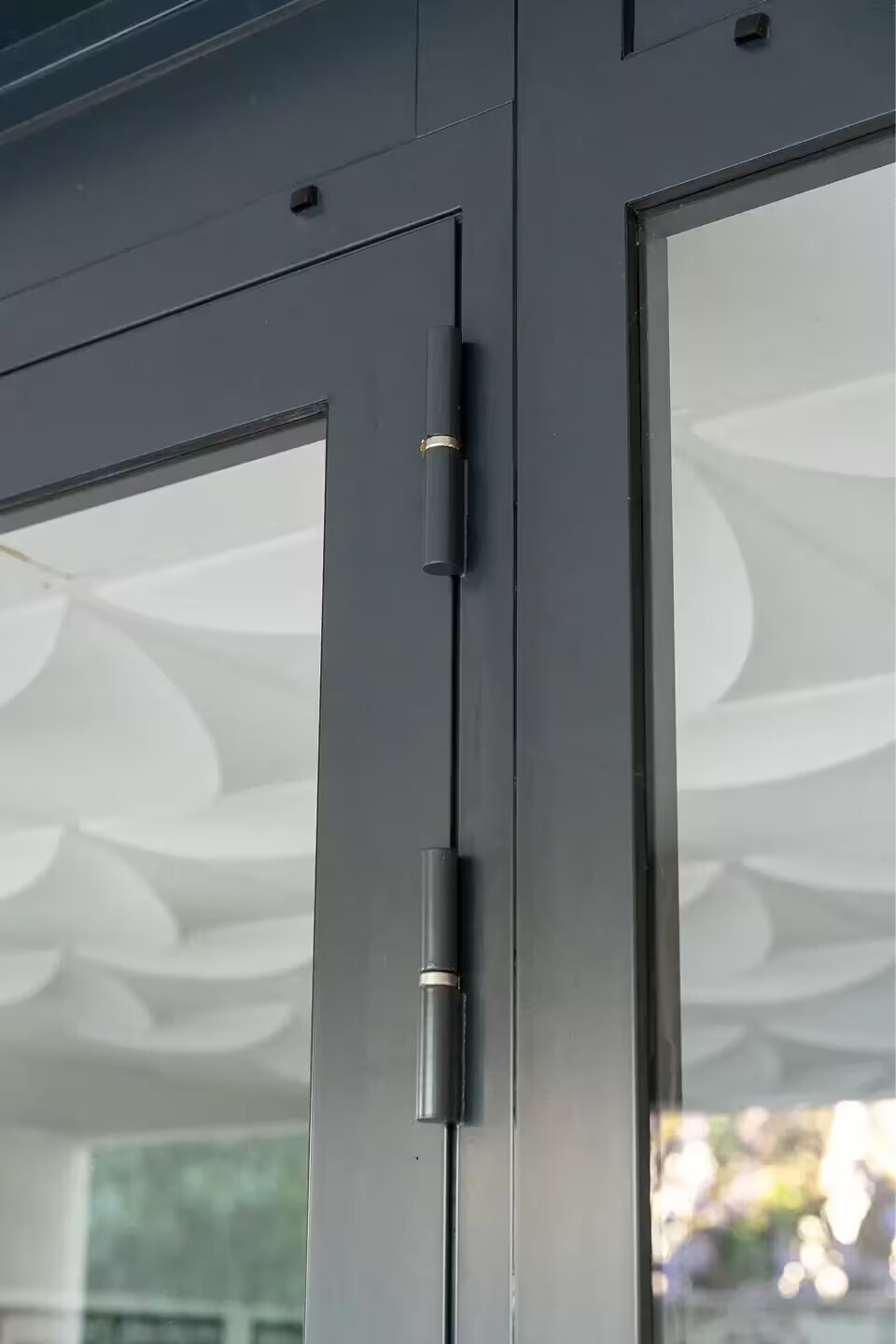 Détail des charnières et de la menuiserie en acier d'une porte de hall d'immeuble à Nantes, finitions soignées par Coyac