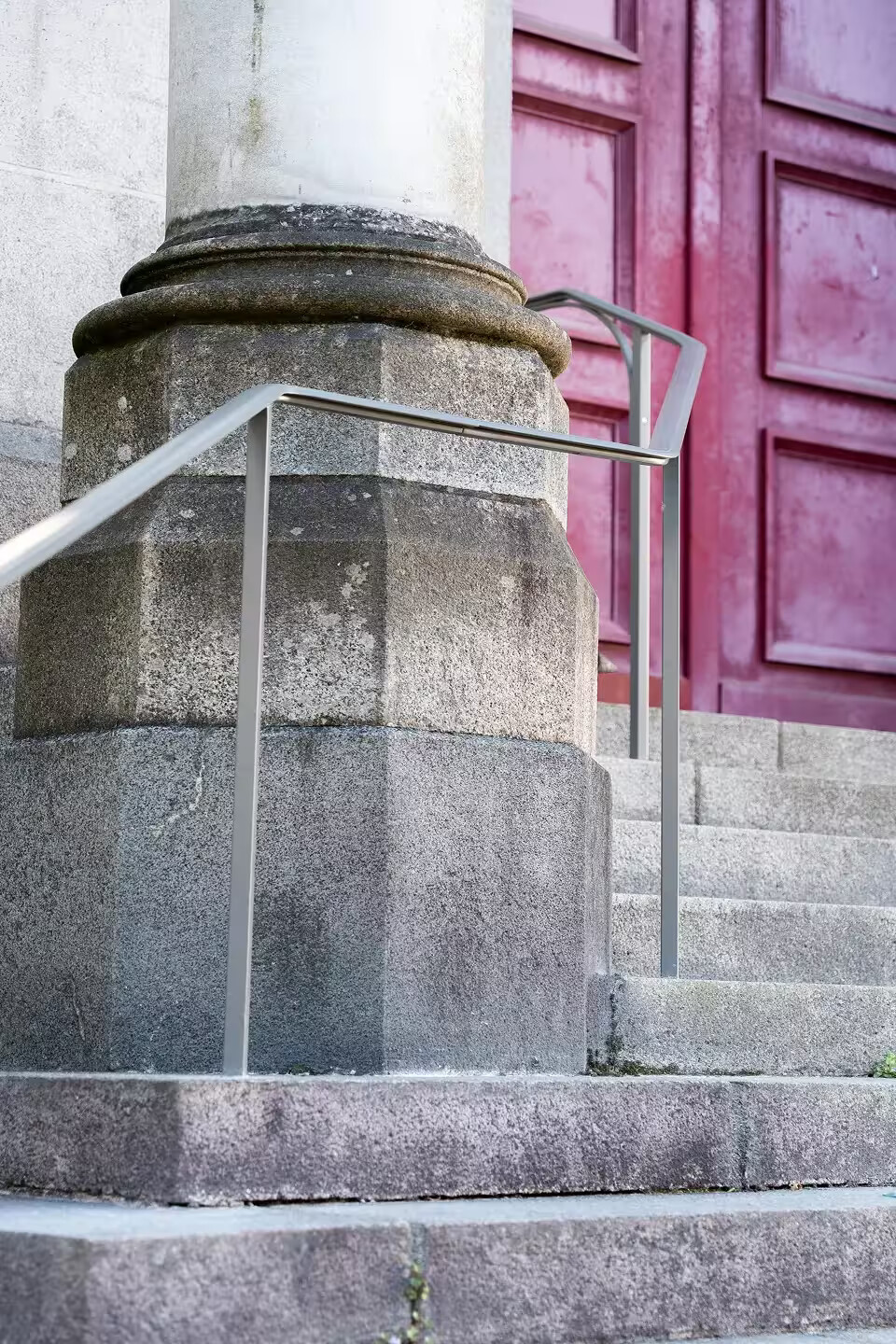 Mains courantes sur-mesure en acier laqué clair posées au pied d'une colonne en granit, devant la porte principale de l'église Notre-Dame de Toute Joie à Nantes