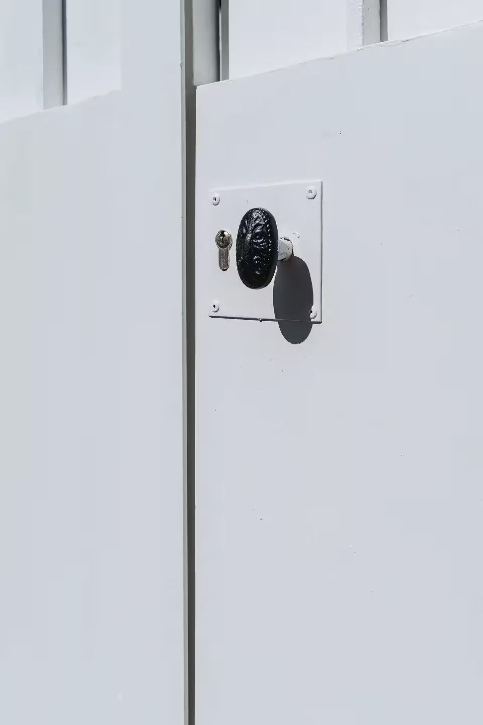 Détail de la nouvelle serrure en applique à cylindre sécurisé et du bouton de tirage en fonte sur un portail en fer forgé rénové par Coyac à Nantes