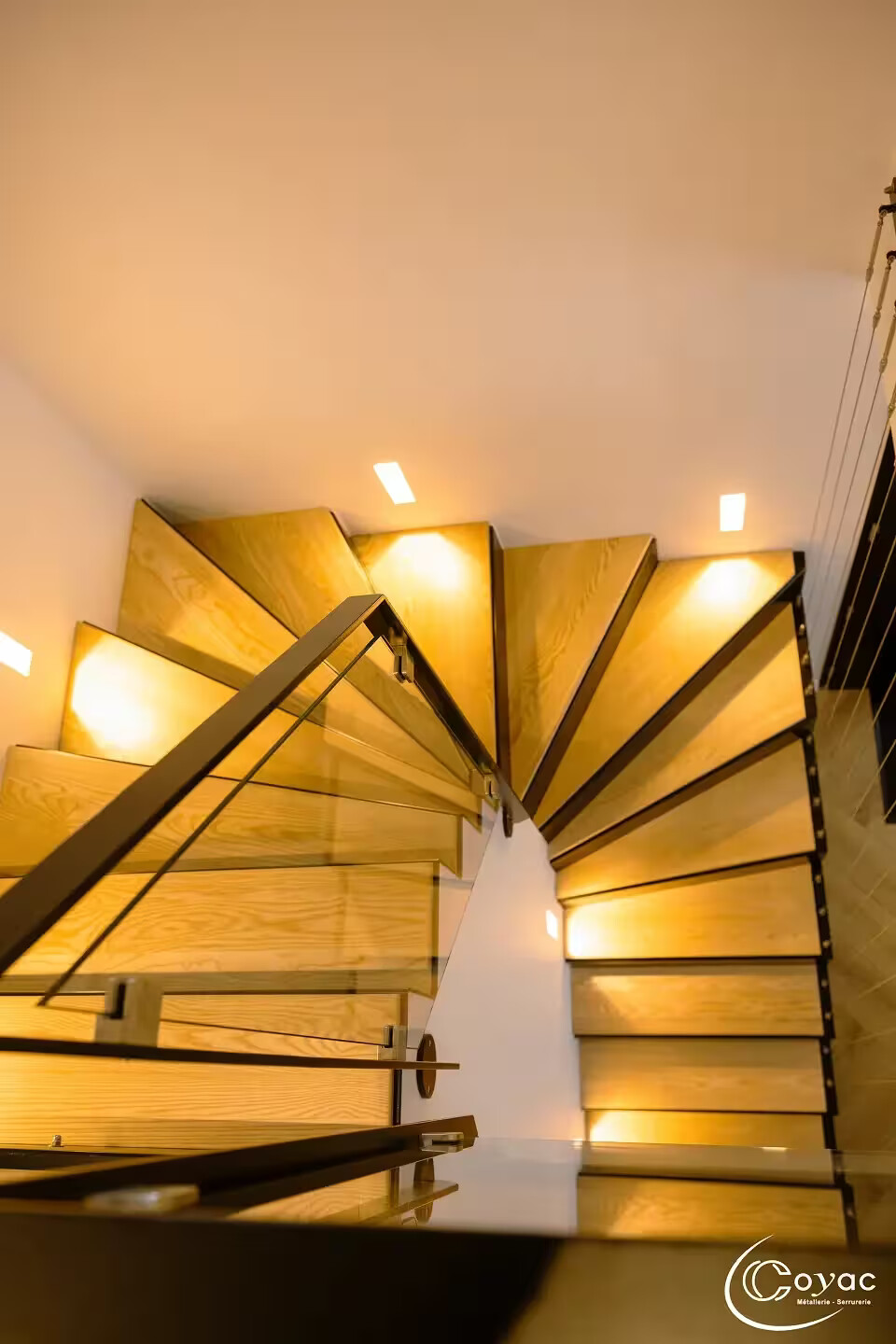 Vue en plongée sur les marches pliées en éventail d'un escalier sur-mesure métal et bois à Savenay, illustrant le tracé technique réalisé par Coyac